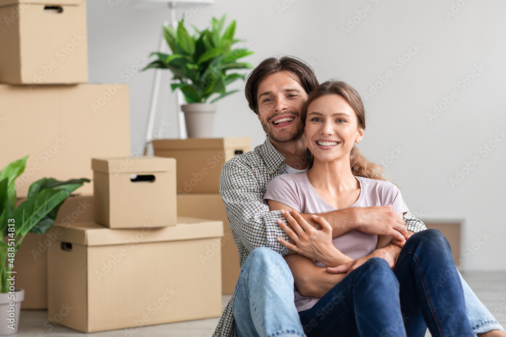 Cheerful excited millennial caucasian male and female in casual hugs, enjoy moving at new flat Cheerful excited millennial caucasian male and female in casual hugs, enjoy moving at new flat