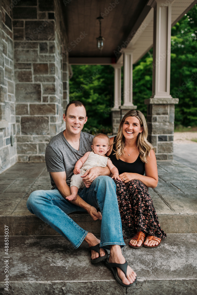 Smiling parents with baby boy sitting on porch Smiling parents with baby boy sitting on porch