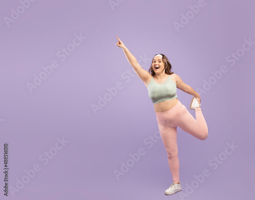 Happy surprised excited plus size european young lady in sportswear doing leg exercise