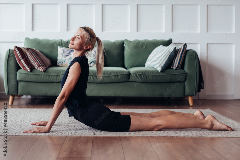 Young woman exercising at home doing an exercise for back flexibility. Young woman exercising at home doing an exercise for back flexibility.