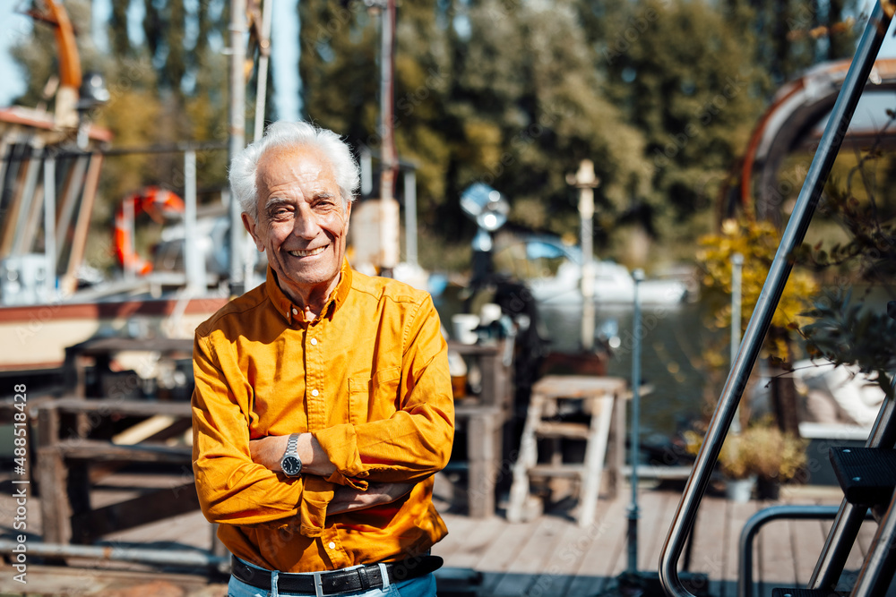 Happy senior man standing with arms crossed on sunny day Happy senior man standing with arms crossed on sunny day
