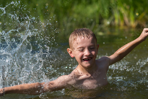 a boy bathes in a river in the summer on a hot day