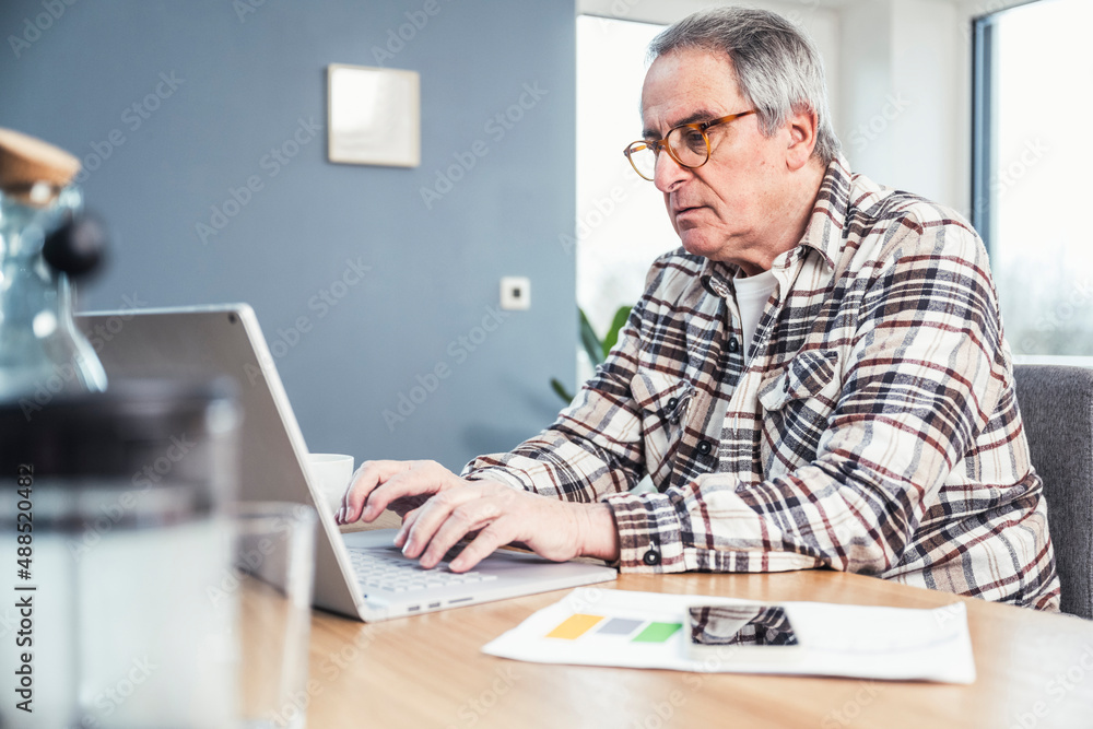 Man typing on laptop sitting at table Man typing on laptop sitting at table