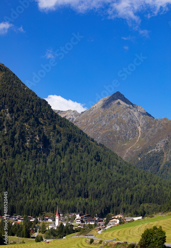 Austria, Tyrol, Sankt Sigmund im Sellrain, Aerial view of village at foot of forested mountain in Sellrain Valley photo