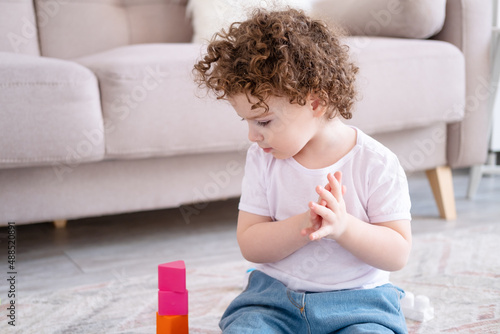 cute curly child girl playing with constructor at home. early children development