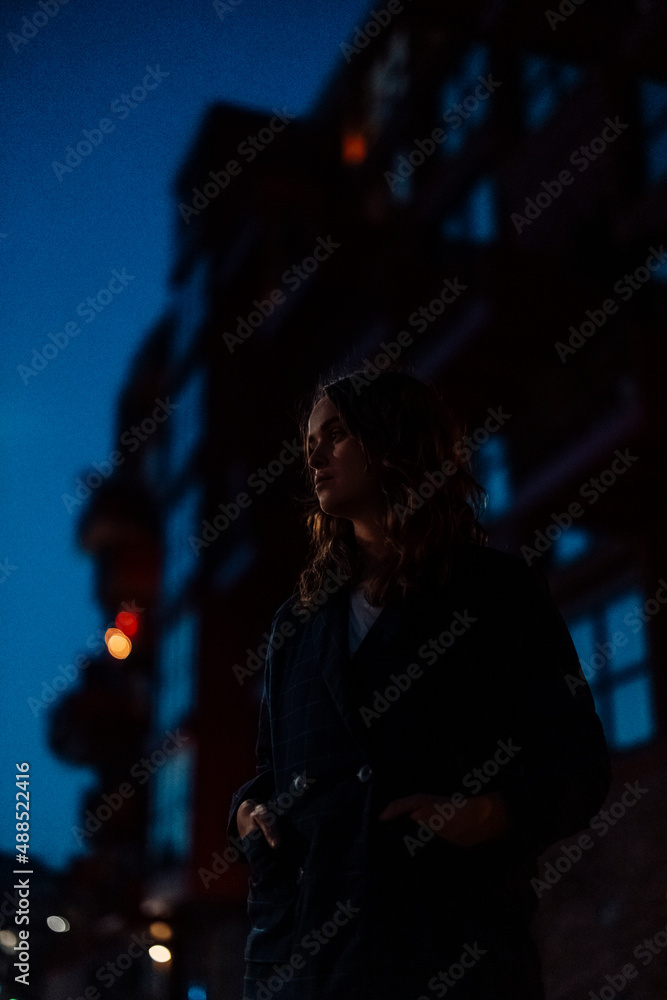 Young woman with hands in pockets on city street at night Young woman with hands in pockets on city street at night