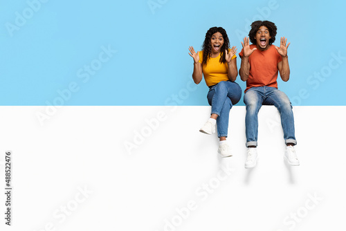 Emotional black man and woman sitting on horizontal board