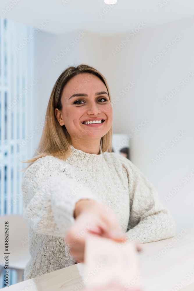 Happy young woman at reception desk in clinic Happy young woman at reception desk in clinic