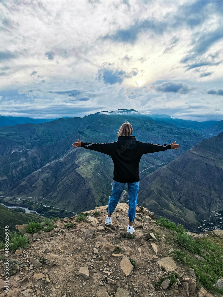 A girl on the background of a mountain view from the ancient village of Goor. Russia, Dagestan 2021