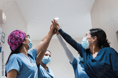 Doctors giving high-five to each other at hospital photo