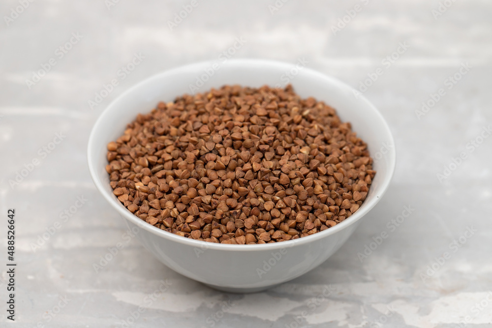 uncooked buckwheat in small white bowl on ceramic uncooked buckwheat in small white bowl on ceramic