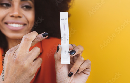 Woman with fingers crossed holding testing kit photo