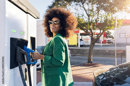 Happy businesswoman with fuel pump at gas station photo
