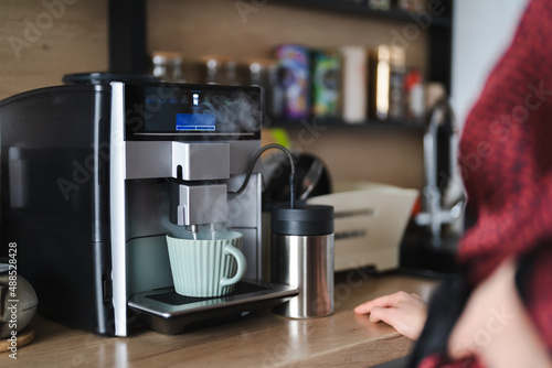 Close-up image of woman hand using coffee machine when making big mug of coffee at home