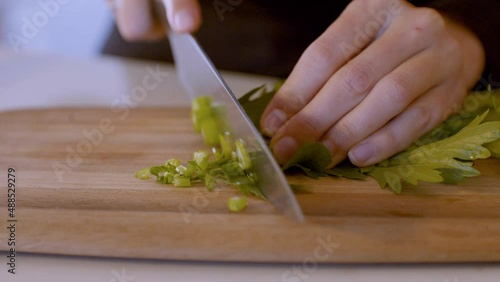 Slicing of fresh celery on wooden board