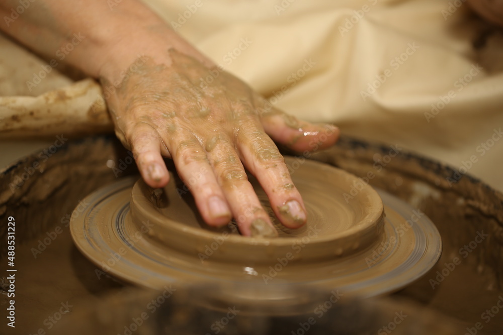 A potter makes a product out of clay, on a potter's wheel. Women's hands. A potter makes a product out of clay, on a potter's wheel. Women's hands.