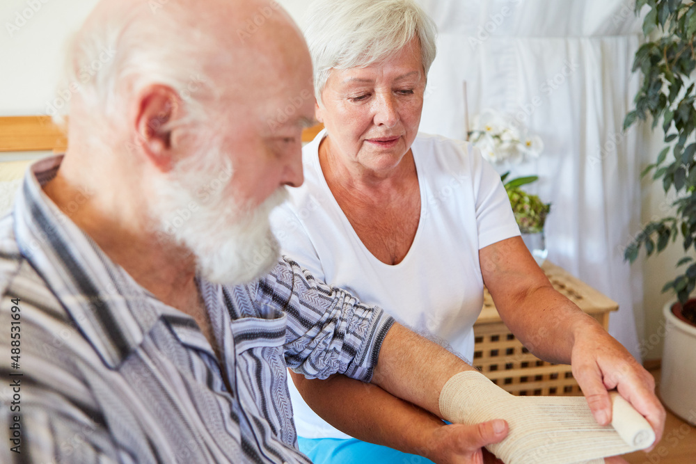 Geriatric nurse connects senior's wrist Geriatric nurse connects senior's wrist