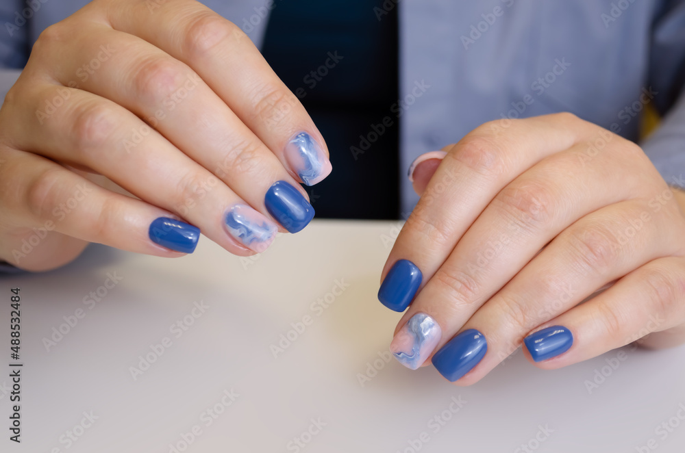 The hand of a young woman with blue gel polish and abstract design. Manicure ideas. The hand of a young woman with blue gel polish and abstract design. Manicure ideas.
