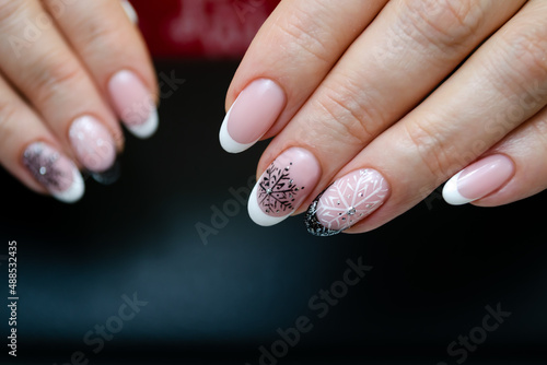 The hand of a young woman with a French manicure and a winter design with snowflakes