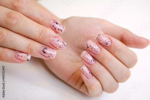 A well-groomed female hand on a white background, manicure with a soft pink gel polish