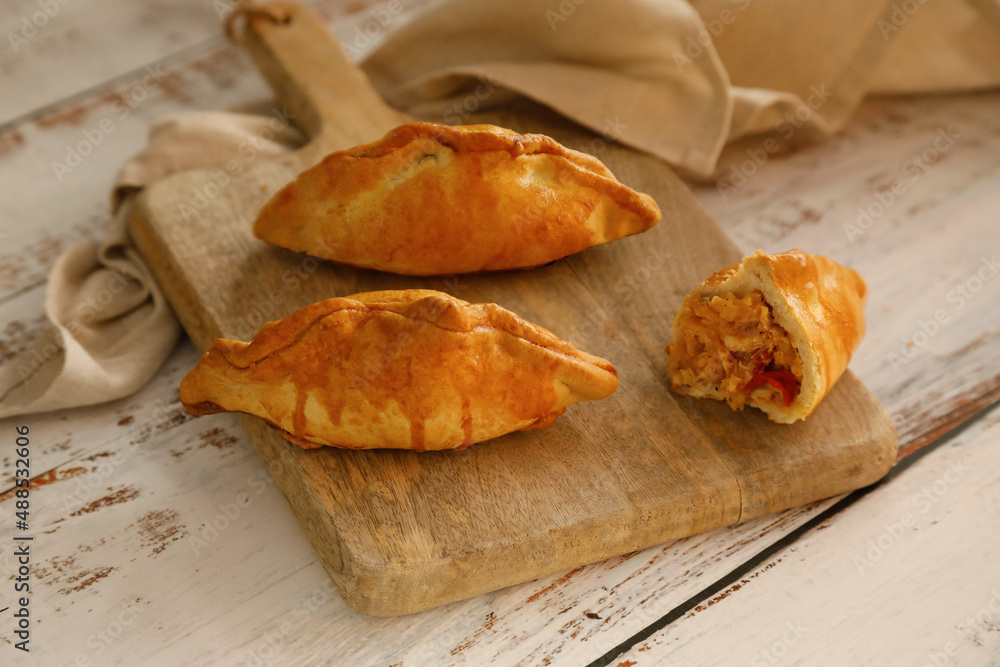 Traditional spanish food: Delicious empanadas stuffed with tuna, tomato and onion on rustic background Traditional spanish food: Delicious empanadas stuffed with tuna, tomato and onion on rustic background