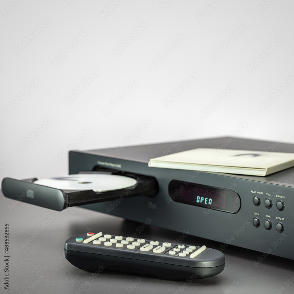 CD player, open disc tray, remote control on the table, close-up. CD player, open disc tray, remote control on the table, close-up.