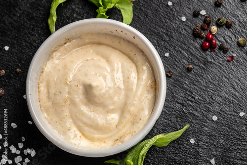 Bowl with garlic sauce on dark background. Food recipe background. Close up