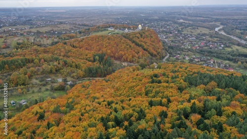 autumn forest in the mountains overlooking the village © Ruslan