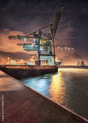 Night scene with gigantic crane on illuminated container terminal, Port of Antwerp, Belgium.