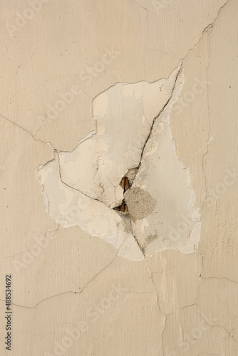 A close-up of the damaged plasterwork on a wall. This plasterwork definitely needs to be repaired.
