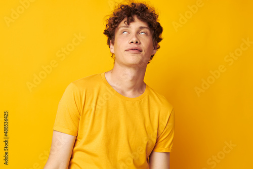 Young curly-haired man wearing stylish yellow t-shirt posing Lifestyle unaltered © Tatiana