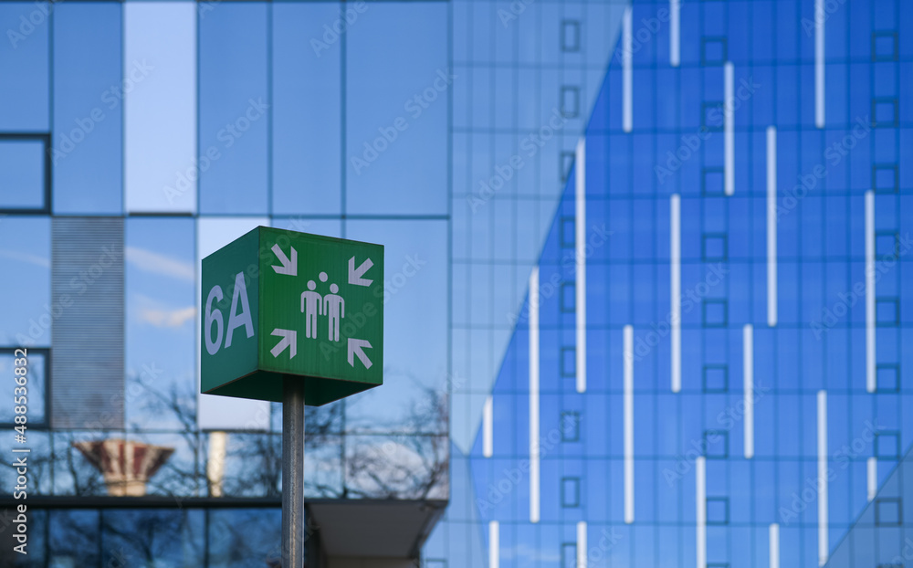 Emergency assembly point in the parking lot of a tall skyscraper office building where a lot of people work in corporation