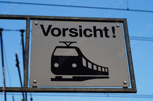 A sign above a pedestrian crossing warns of approaching trains. photo