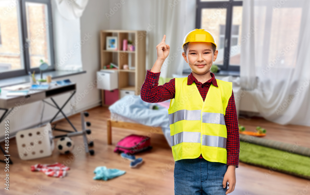 building, construction and profession concept - little boy in protective helmet and safety vest pointing finger up over children's room at home background building, construction and profession concept - little boy in protective helmet and safety vest pointing finger up over children's room at home background