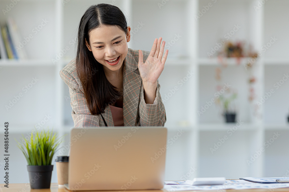 Beautiful Asian businesswoman sitting in her private office, she is talking to her partner via video call on her laptop, she is a female executive of a startup company. Concept of financial management Beautiful Asian businesswoman sitting in her private office, she is talking to her partner via video call on her laptop, she is a female executive of a startup company. Concept of financial management