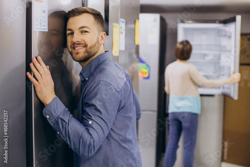 Man hugging refrigerator at electricity store