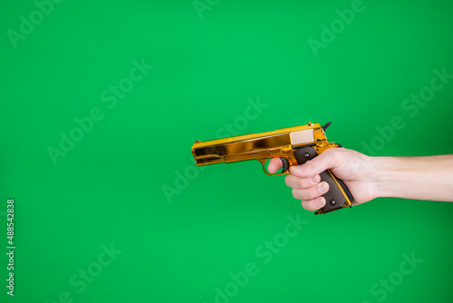 golden pistol in hand on a green background