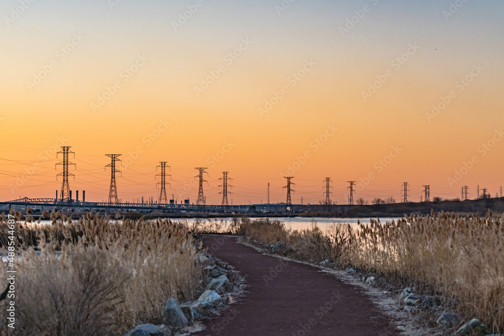 Power lines starching across the horizon in urban park environment during vivid morning, colorful morning sky.
