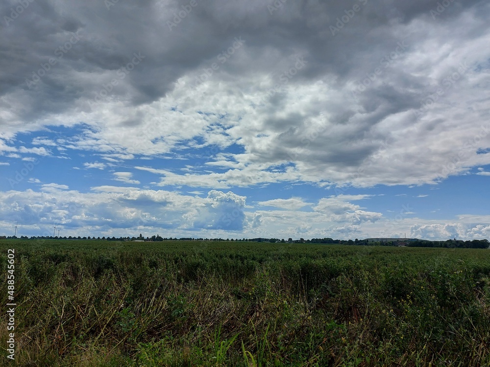 Bewölkter Himmel vor dem Sturm. Graue, schwere Wolken über dem Feld. Die Agrarlandschaft vor dem Sommerregen. Gepflügte Felder so weit das Auge reicht, bereit zur Aussaat. Eine ländliche Straße. Bewölkter Himmel vor dem Sturm. Graue, schwere Wolken über dem Feld. Die Agrarlandschaft vor dem Sommerregen. Gepflügte Felder so weit das Auge reicht, bereit zur Aussaat. Eine ländliche Straße.