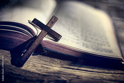 Praying with wooden crucifix cross on Holy Bible background