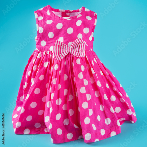 pink baby dress with white polka dots, on a turquoise background, concept