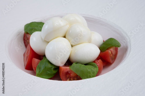 Tasty caprese salad with cherry tomatoes, white mozzarella cheese and green basil leaves