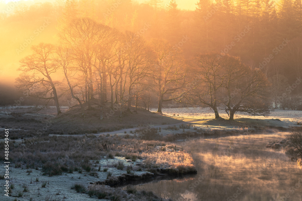 Breathtaking golden light illuminating frosty Winter landscape with misty river near Elterwater in the Lake District, UK. Breathtaking golden light illuminating frosty Winter landscape with misty river near Elterwater in the Lake District, UK.