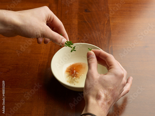 hands putting an aromatic herb to make a sauce in the kitchen © ArtiFicio