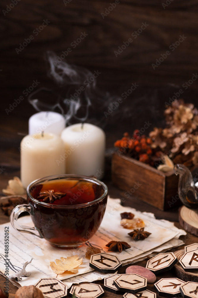 Wooden runes are lying on the table among the papers with notes. There is a mug of tea next to it. Astrology and esotericism. Wooden runes are lying on the table among the papers with notes. There is a mug of tea next to it. Astrology and esotericism.