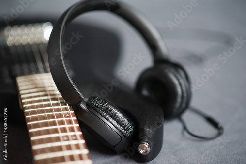 Black headphones on black electric guitar. Musical lifestyle. 
