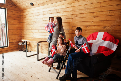 Family with Denmark flags inside wooden house. Travel to Scandinavian countries. Happiest danish people's .