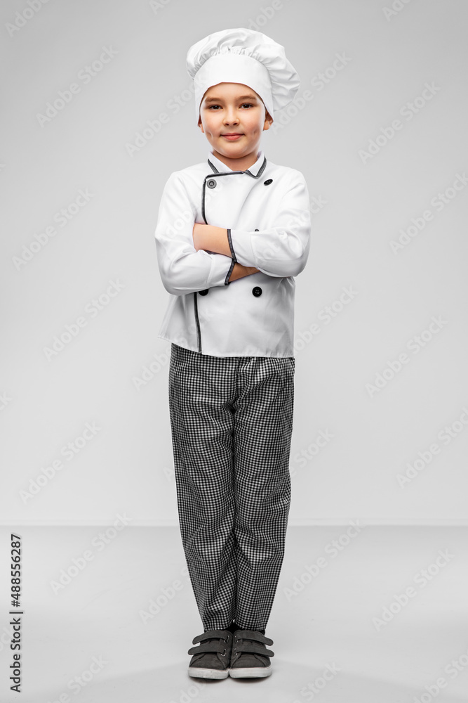 cooking, culinary and profession concept - happy smiling little boy in chef's toque and jacket over grey background cooking, culinary and profession concept - happy smiling little boy in chef's toque and jacket over grey background