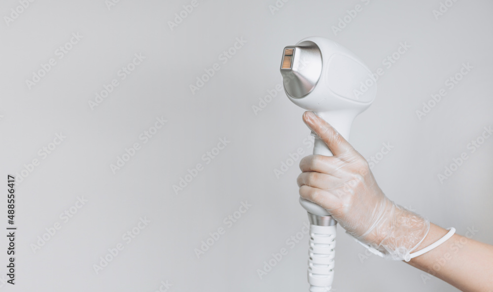 Laser device for removing unwanted hair in the hand of nurse. Laser hair removal, cosmetic body treatments. Concept of hygiene, beauty, health. Girl holding a working part of the epilator in her hand