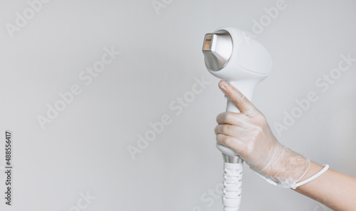 Obraz na płótnie Laser device for removing unwanted hair in the hand of nurse. Laser hair removal, cosmetic body treatments. Concept of hygiene, beauty, health. Girl holding a working part of the epilator in her hand w salonie